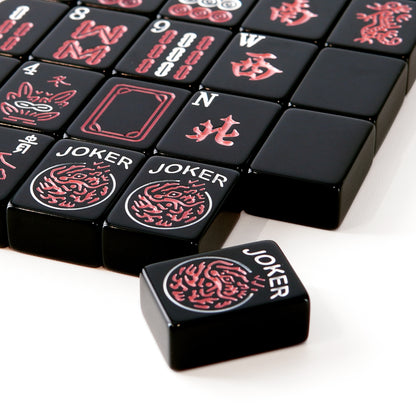 black mahjong tiles displayed with matching dice and a compact storage case