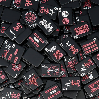 black mahjong tiles scattered closely together showing red and white symbols on a dark surface